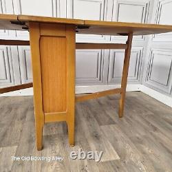 Table de salle à manger en bois de teck avec rabats rétractables style rétro vintage du milieu du XXe siècle.